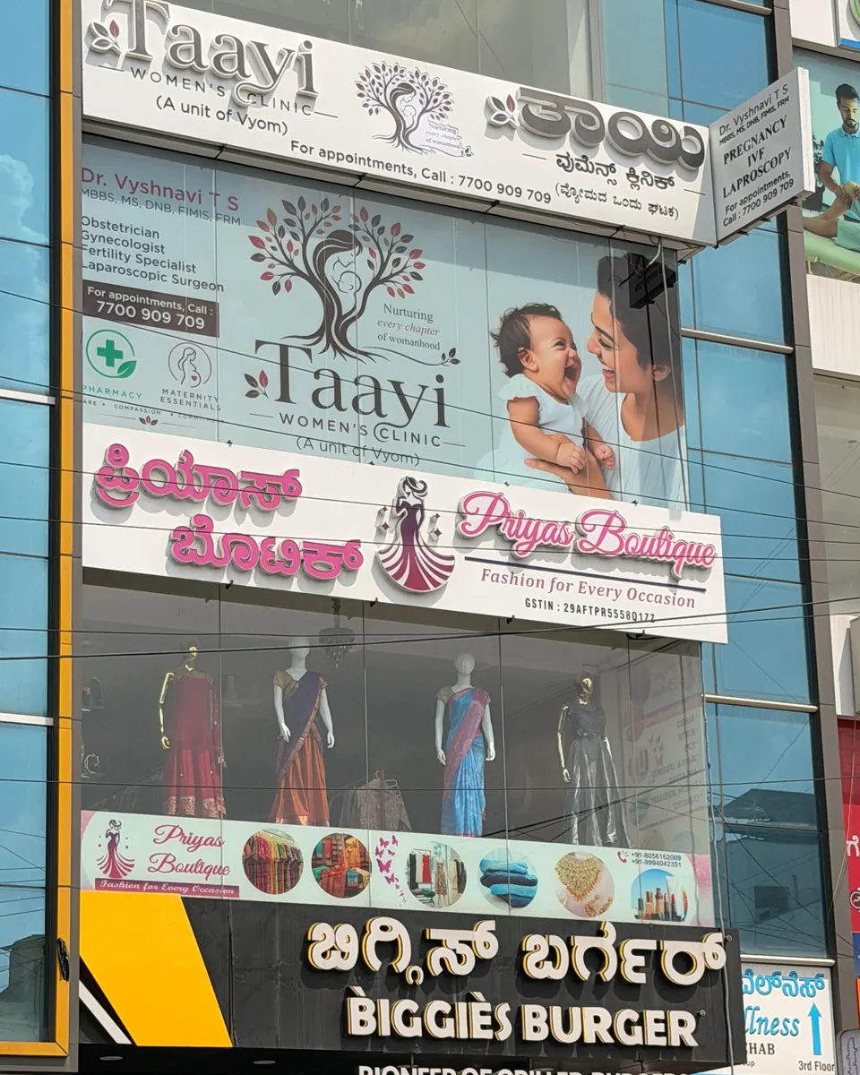 The Taayi Women's Clinic signboard on the building front, above Biggies Burger on Hoodi Main Road