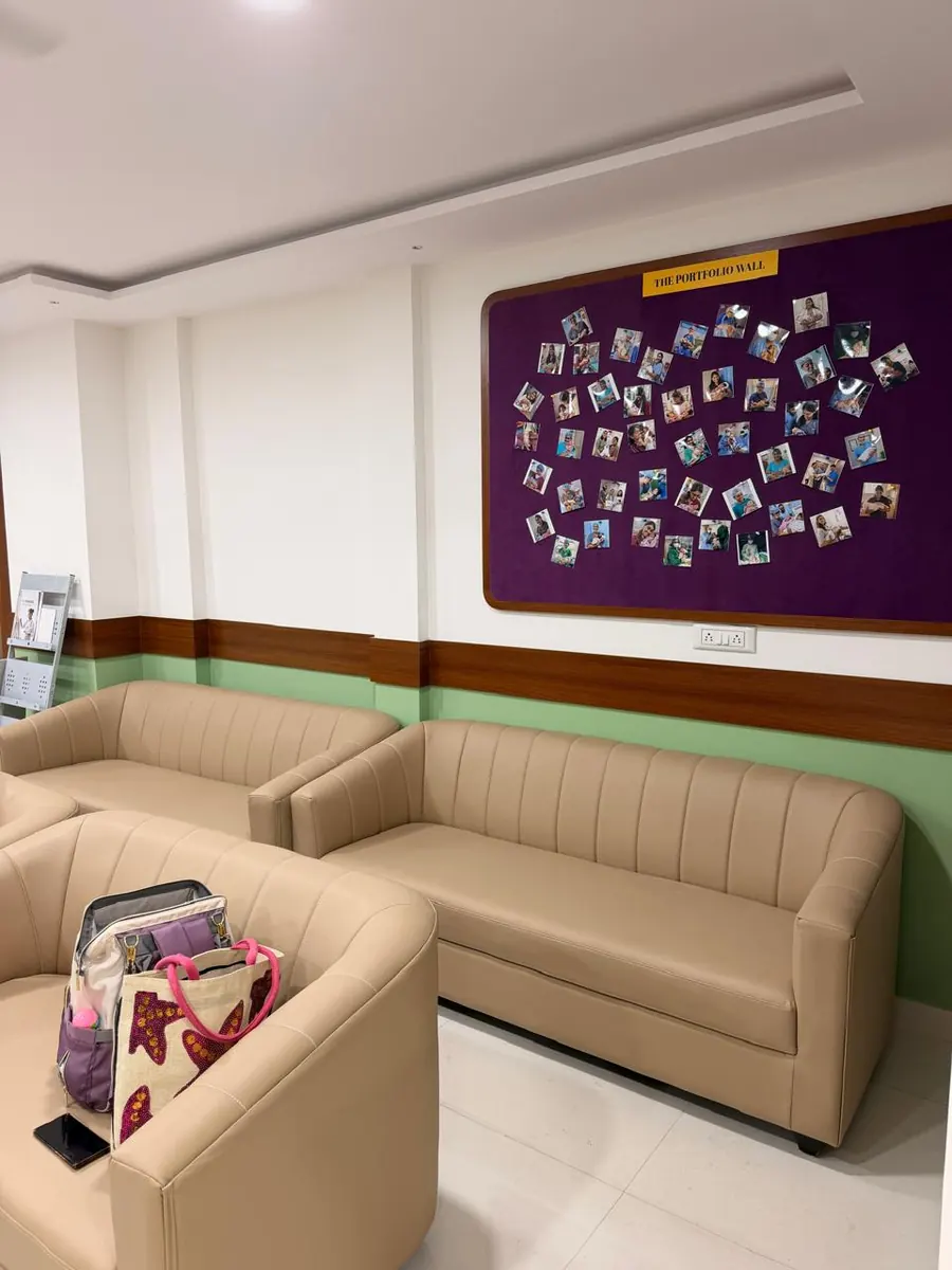 A purple board of photographs above the waiting-area sofas