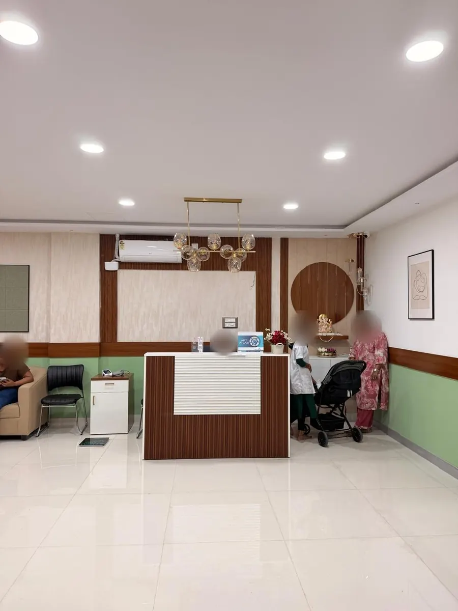 The clinic reception desk with a wood-panelled wall and a glass pendant light
