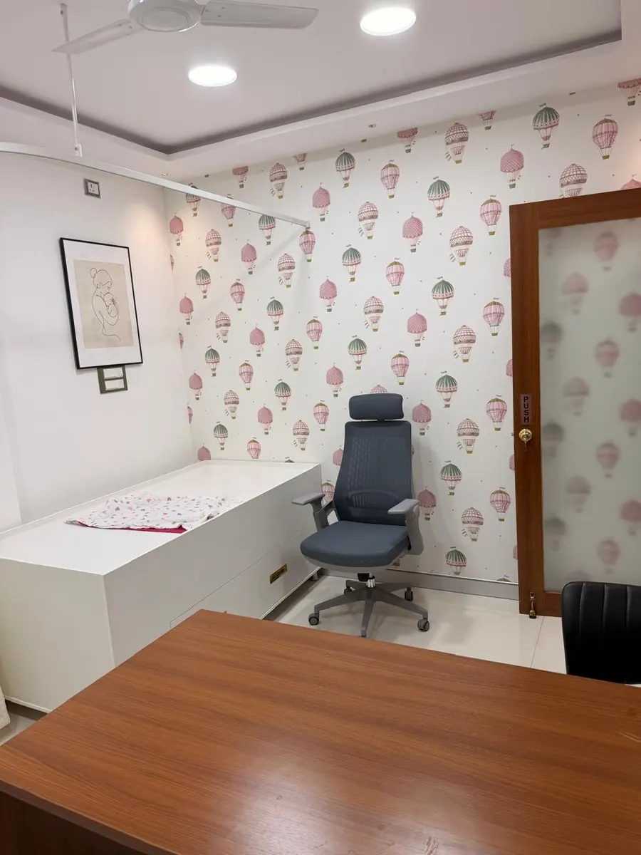A consultation room with hot-air-balloon wallpaper and an examination couch